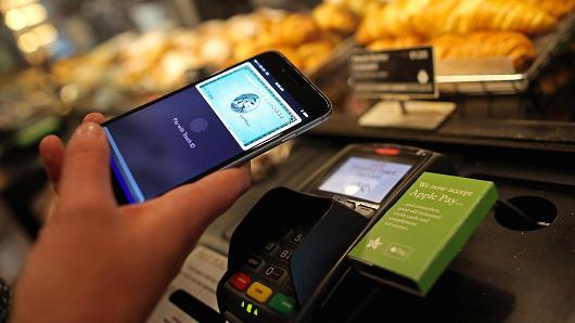 A women uses American Express’ mobile tap feature at the grocery store checkout.