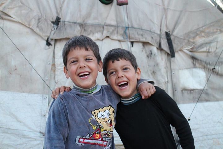 Twins, Ahmed and Mahmoud, laugh together in a refugee camp in Syria. 