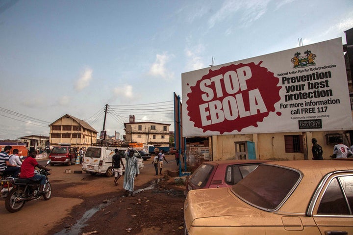 People pass a banner during Sierra Leone’s Ebola free campaign in the city of Freetown, Jan. 15, 2016.