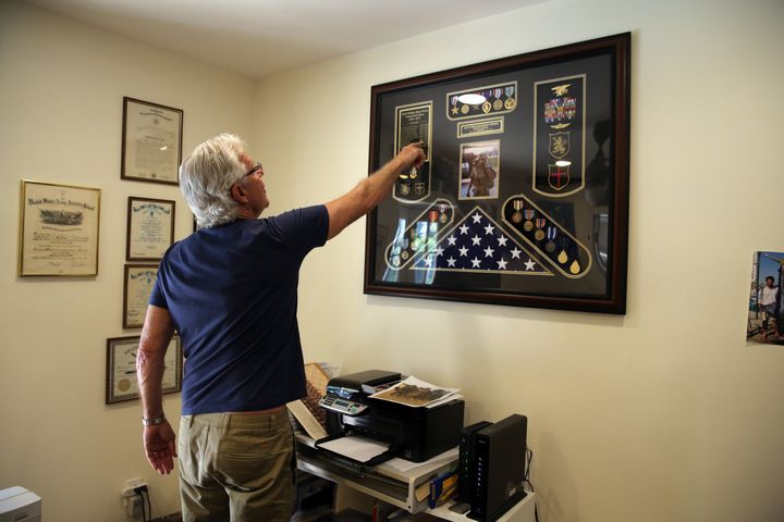 Owens points to a display of his son's medals and honours 