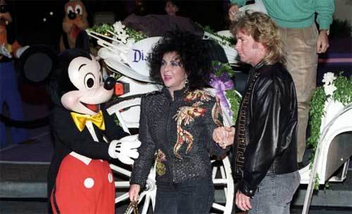 Mickey greets Elizabeth Taylor as the birthday girl, Larry Fortensky & Michael Eisner alight from their horse-drawn coach.