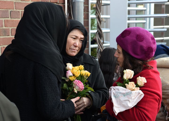 Refugees from Iran hold flowers during a demonstration against violence in Cologne, Germany, on Jan. 22, 2016. 