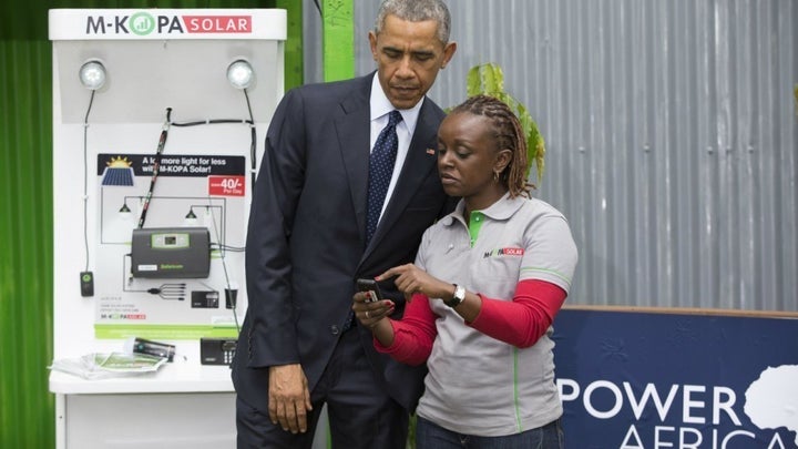 An agent in Nairobi explains to former US President Barack Obama how a social-enterprise organisation is helping rural house-holds access solar energy systems for which they pay in daily installments using the mobile money platform Mpesa.