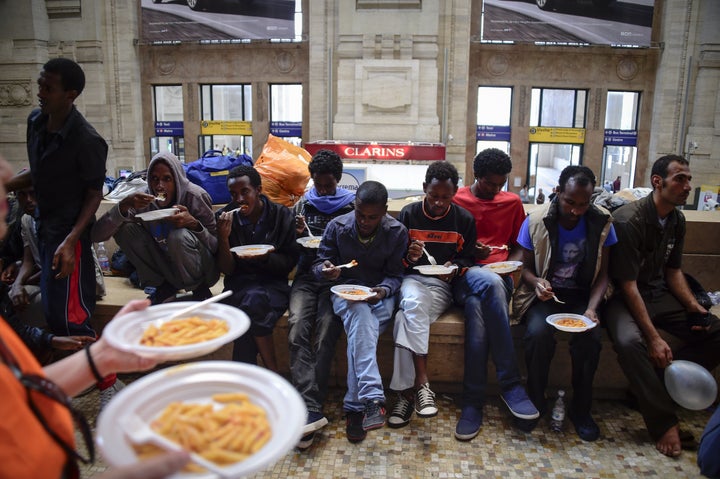 Migrants from Eritrea eat a meal they received at a Milan train station in 2015.