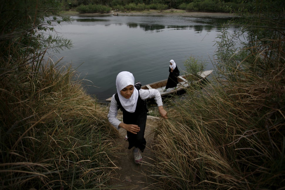An Iraqi school girl walks up the bank of a river after crossing the waterway on a small wooden boat in the district of Al-Mi