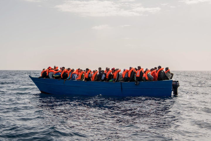 Migrants and refugees are assisted by members of the Spanish NGO Proactiva Open Arms as they crowd on board of a wooden boat