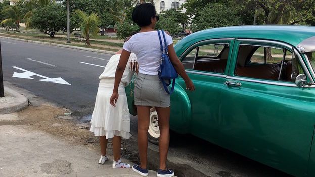 Two women board a shared taxi (almendrón) in Havana. 