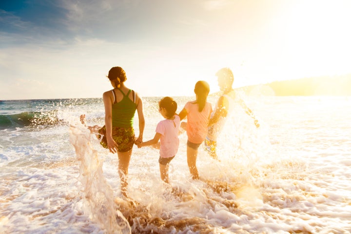happy young family playing on beach at sunset Tomwang112 via Getty Images