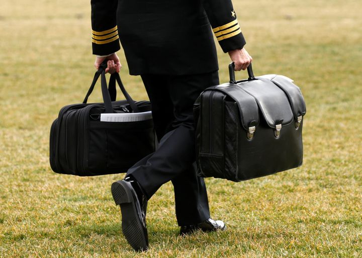 A military aide to Donald Trump carrying the so-called 'football' in February which contains the codes for America's nuclear weapons