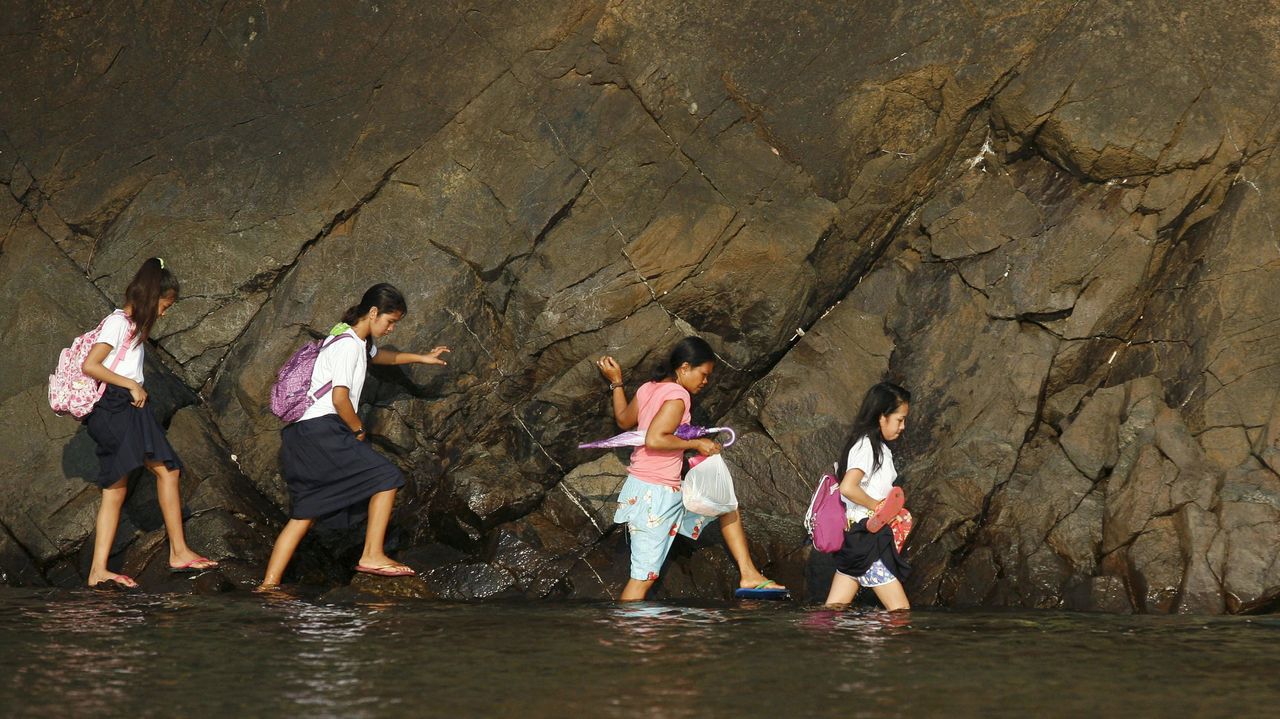 Young girls wade through water to get to school in Manila, Philippines. 