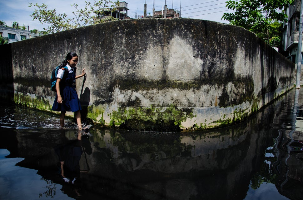 A school going girl walks through a water logged street in Dhaka, Bangladesh, 01 October 2013. Climate change in Bangladesh i