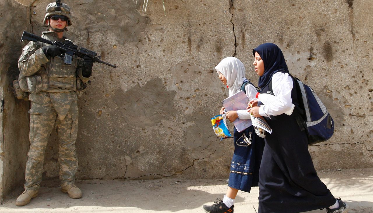 Students walk past a U.S. soldier in Baghdad's Ameen district on October 14, 2008.