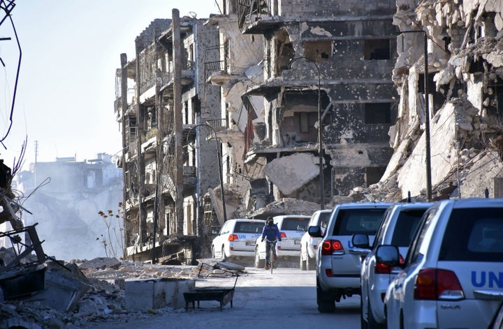 A UN convoy drives past damaged buildings in the eastern neighborhoods of Aleppo. 