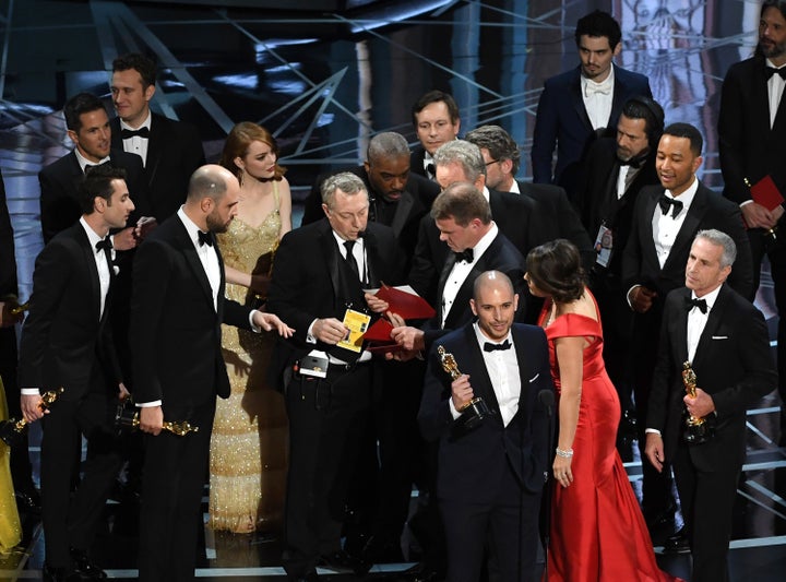 Brian Cullinan and Martha Ruiz appear onstage at the Oscars with a stagehand to look over envelopes.