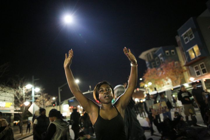 Amanda Ashe of Oakland raises her hands as a police helicopter circles overhead during demonstrations in Emeryville, California, after a grand jury decided there would be no charges in Michael Brown's death in November 2014.