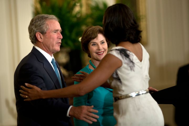 Obama reaches to embrace Bush and wife, Laura, during a portrait unveiling ceremony.
