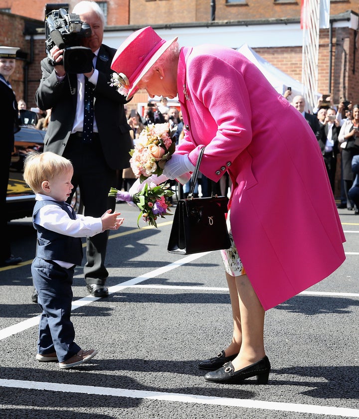 Queen Elizabeth II carrying a Launer hand bag, identifiable by the gold logo on the bag. 