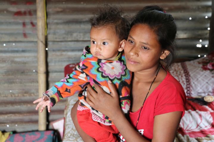 Sumina Pariyar, 17, holds up her baby daughter in their tin shack near a congested highway overpass in Kathmandu, Nepal. Sumina married as a teen and was pregnant in her husband's remote village when the Nepal earthquake struck and destroyed their home.