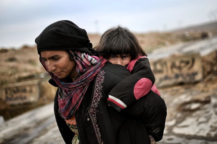 An Iraqi woman and her child walk down a road as they flee Mosul on March 3, 2017. 