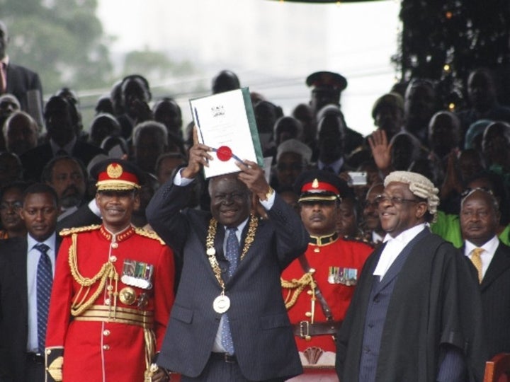 Former President Mwai Kibaki holds up the new constitution with a national seals during the promulgation of the new constitut