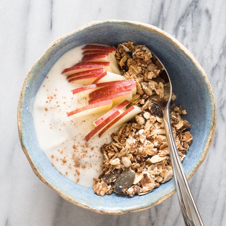 Bowl of homemade granola with apple slices, plain yogurt and cinnamon InaTs via Getty Images