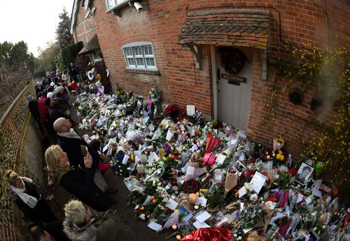 Flowers, messages and candles have been left in tribute outside George Michael's home.