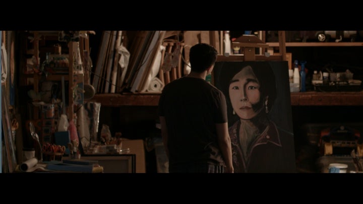 Thomas (Daniel Chan) looks at his long-abandoned painting of his mother in a scene from Song on Canvas 