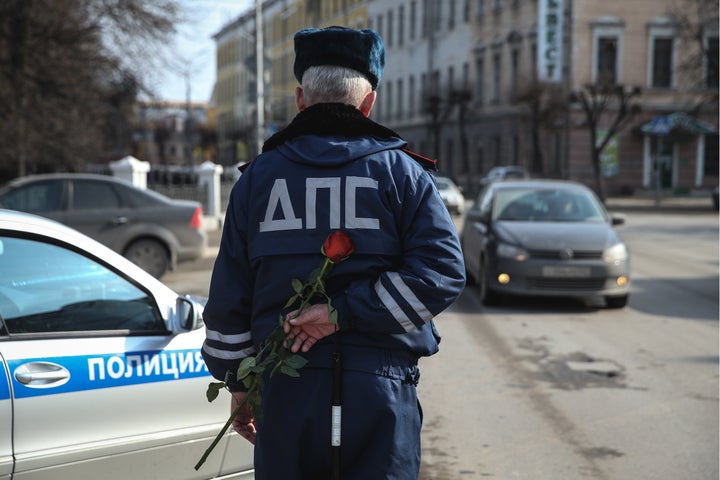 A traffic cop hides a rose before stopping a female driver.