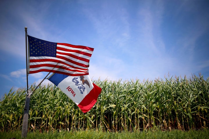 U.S. and Iowa state flags are seen next to a corn field in Iowa. The state has been the site of a long-standing battle b