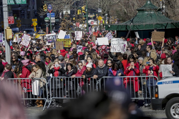 Demonstrators lift their signs outside Trump Hotel during the Day Without a Woman strike in Manhattan.