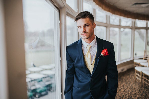 Your handsome groom can channel the beast in a navy tux paired with a gold tie and vest. Complete the look with a single rose boutonniere. Related: Beyond the Black Tux: Stylish Groom Inspiration