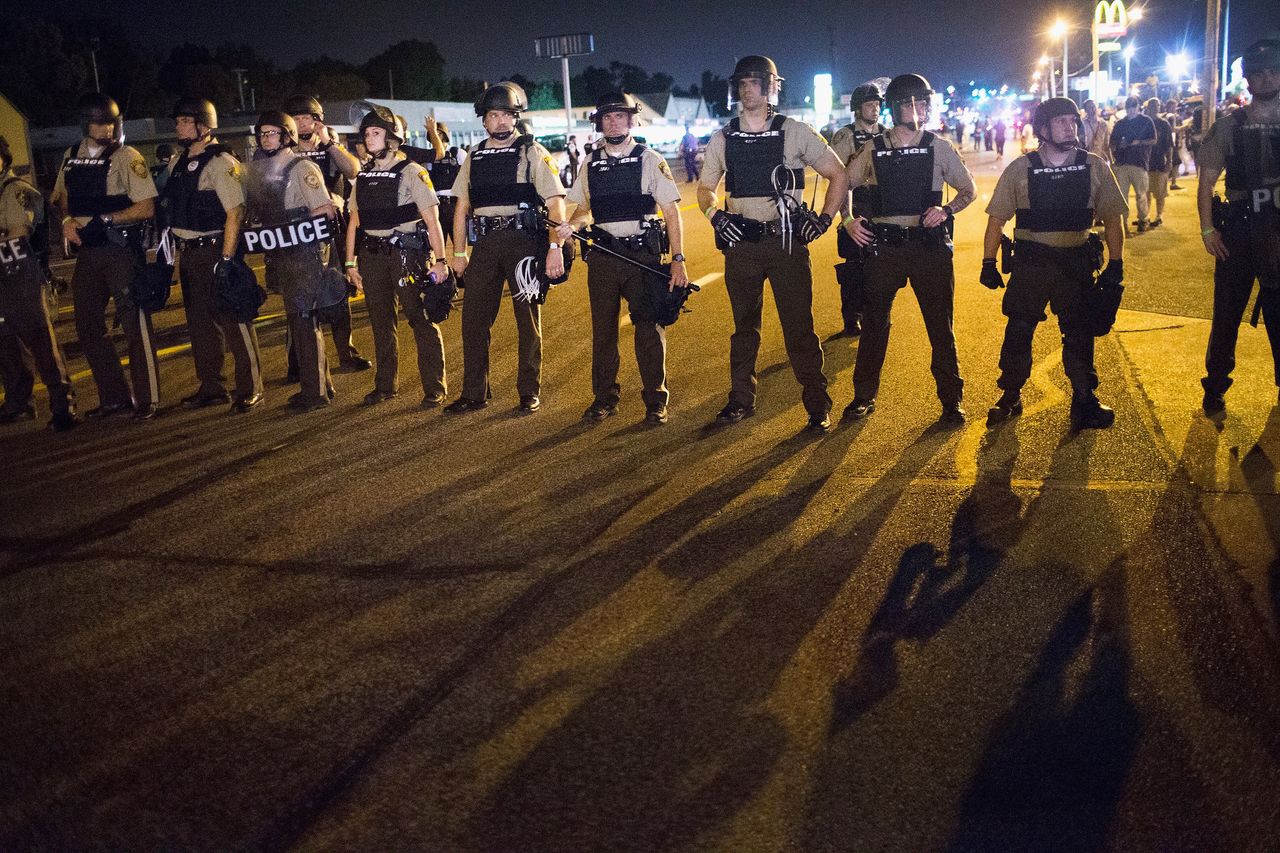 Police stand guard as demonstrators mark the first anniversary of the shooting of Michael Brown in Ferguson, Missouri, on Aug. 10, 2015. More than 100 people were arrested in Ferguson and St. Louis.