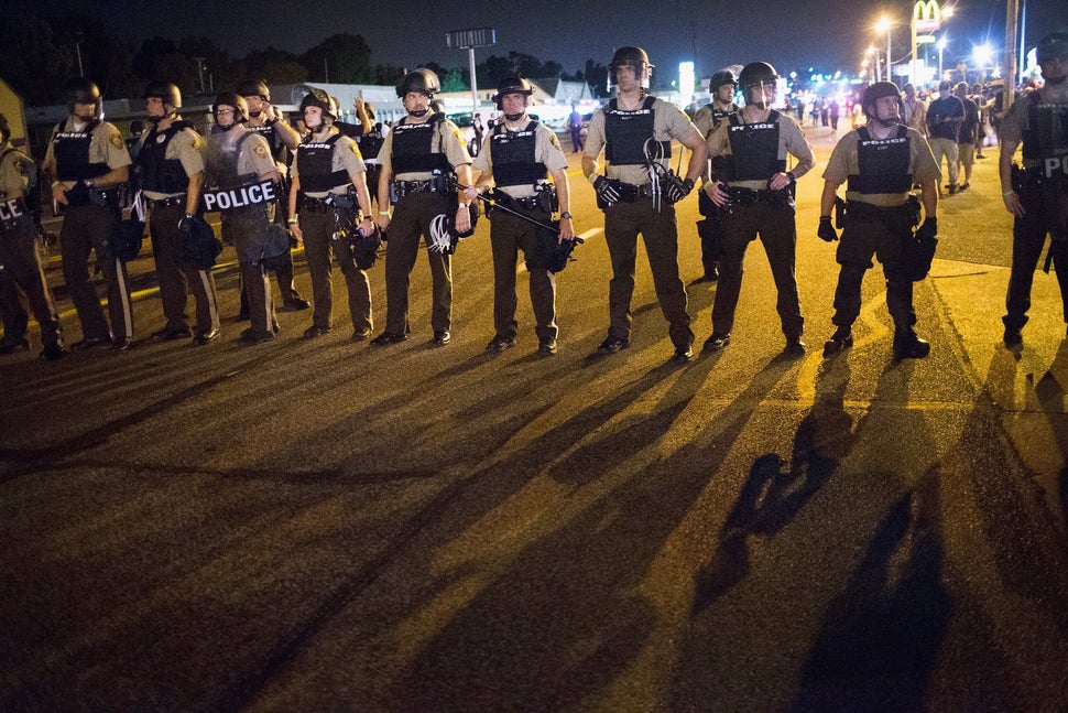 Police stand guard as demonstrators mark the first anniversary of the shooting of Michael Brown in Ferguson, Missouri, on Aug