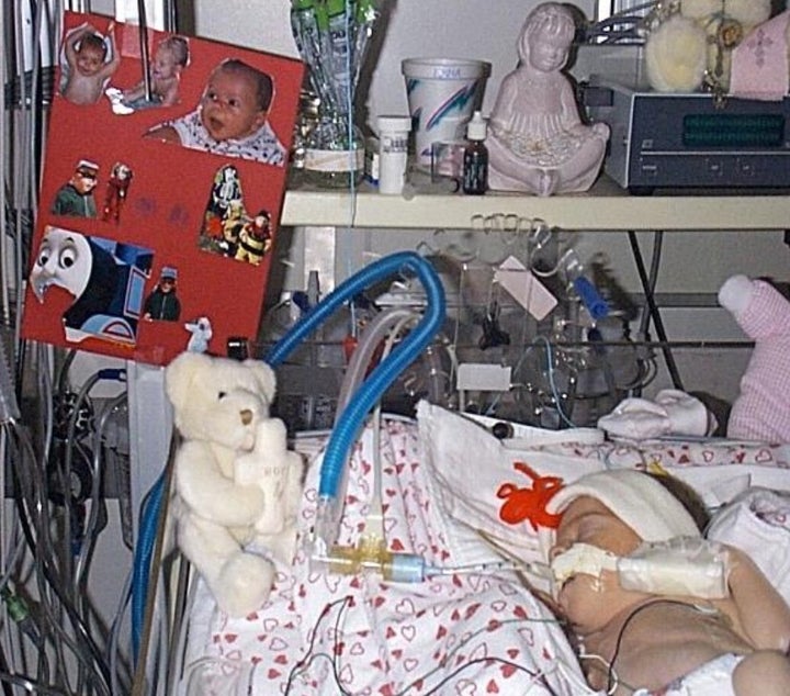 Emma in the NICU, surrounded by photos of her big brother, Luke.