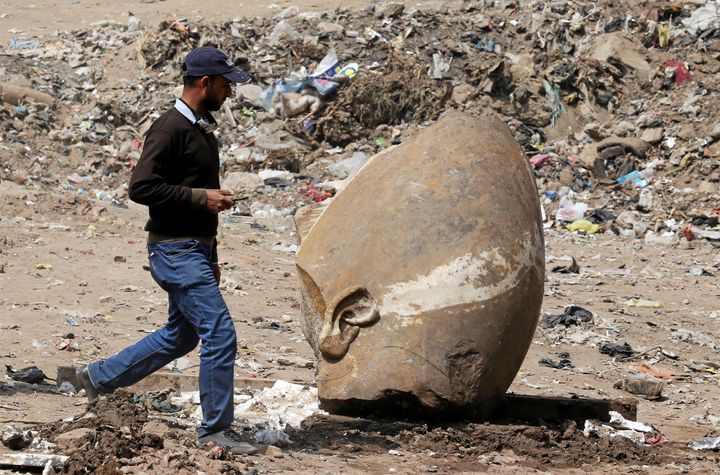 A man passes by what appears to be the head of the unearthed statue