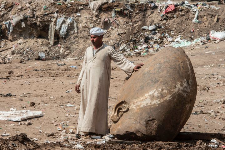 An Egyptian worker stands next to the head of a massive statue that may portray Ramses II on March 9, 2017