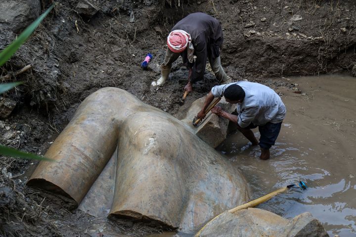 Workers help uncover the torso of what's likely a statue of Ramses II.