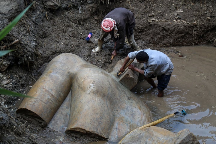 Workers help uncover the torso of what's likely a statue of Ramses II.