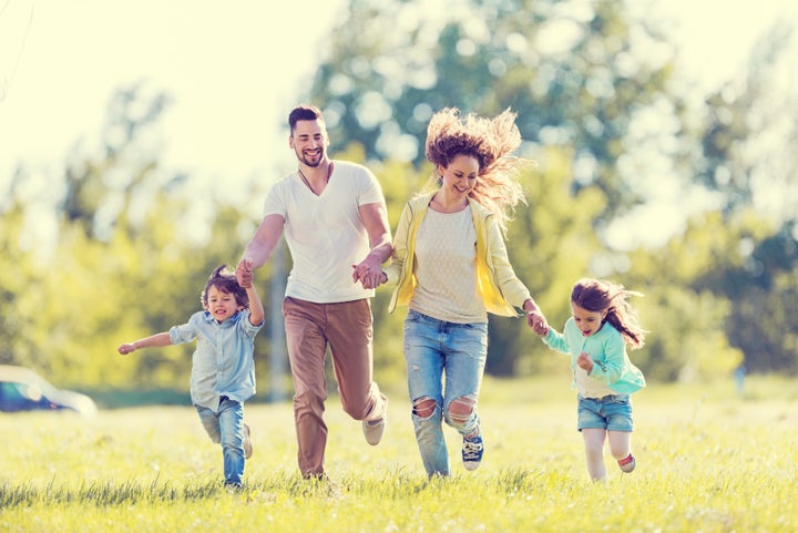 Happy young family running in the park and having fun. BraunS via Getty Images