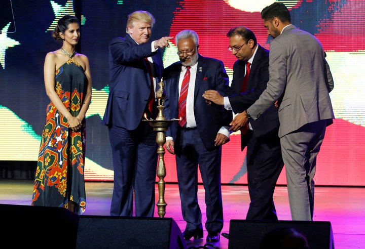 Republican Hindu Coalition Chairman Shalli Kumar (C) stands with Republican presidential nominee Donald Trump (2nd L) to light a ceremonial diya lamp before he speaks at a Bollywood-themed charity concert put on by the Republican Hindu Coalition in Edison, New Jersey, U.S. October 15, 2016.