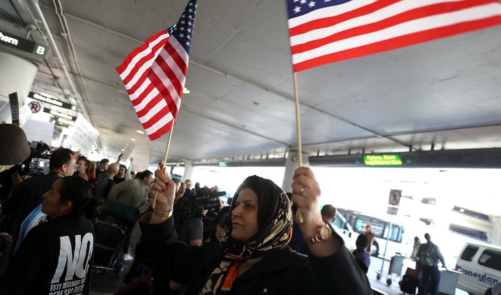 A protester waves American flags during a demonstration against the immigration ban that was imposed by U.S. President Donald