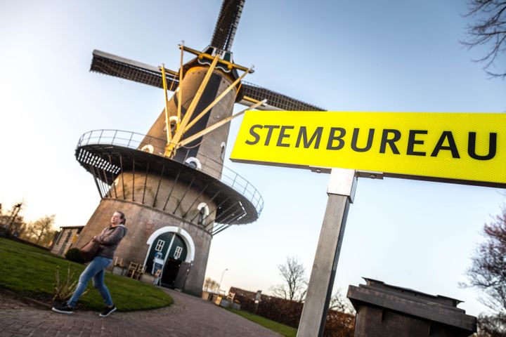 A woman walks past a windmill as voters participate in the Dutch general elections.