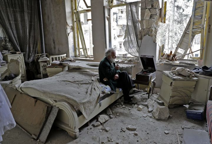 Mohammed Mohiedin Anis, or Abu Omar, 70, smokes his pipe as he sits in his destroyed bedroom listening to music on his gramophone in Aleppo’s formerly rebel-held al-Shaar neighborhood on March 9. 
