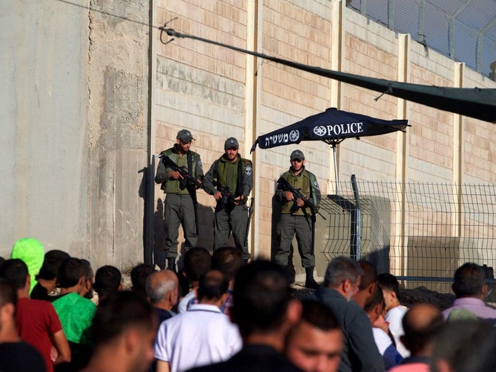 Israeli Border Police officers stand guard as Palestinians wait to cross through the Qalandiyah checkpoint, June 2016. Mohamad Torokman/Reuters