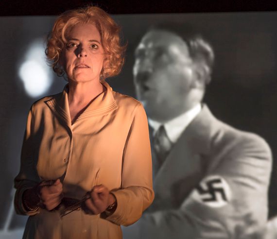 Stacy Ross as Leni Riefenstahl, defending herself; behind her, an image from Triumph of the Will