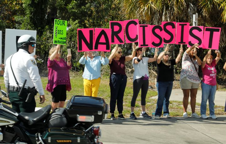 Anti-Trump protesters hold up signs as the motorcade of US President Donald Trump passes by in West Palm Beach, Florida, on Sunday