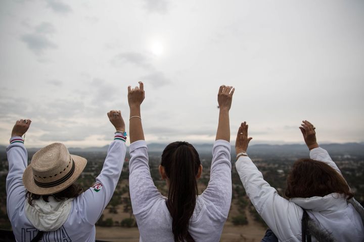 Visitors stretch their arms toward the sun during spring equinox celebrations atop the Pyramid of the Sun in Teotihuacan, Mexico on March 21, 2016