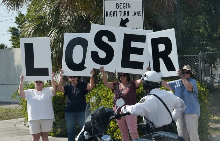 Protestors are seen as the motorcade of US President Donald Trump passes by en route to Palm Beach International Airport in West Palm Beach, Florida on Sunday