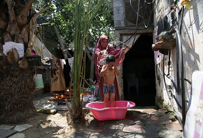 Gaza mother Rawda bathes her children using water from the new network installed in her village. 