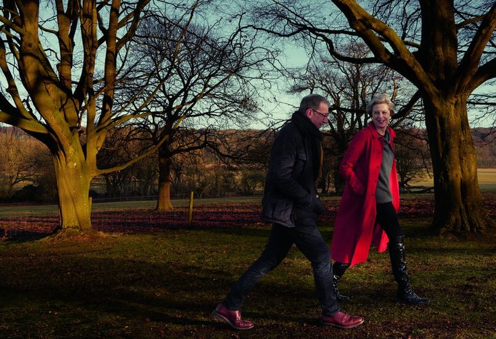 Theresa May pictured in a £450 Egg coat, a £470 Sine for Egg sweater and black boots walking in the countryside with her husband, Philip.